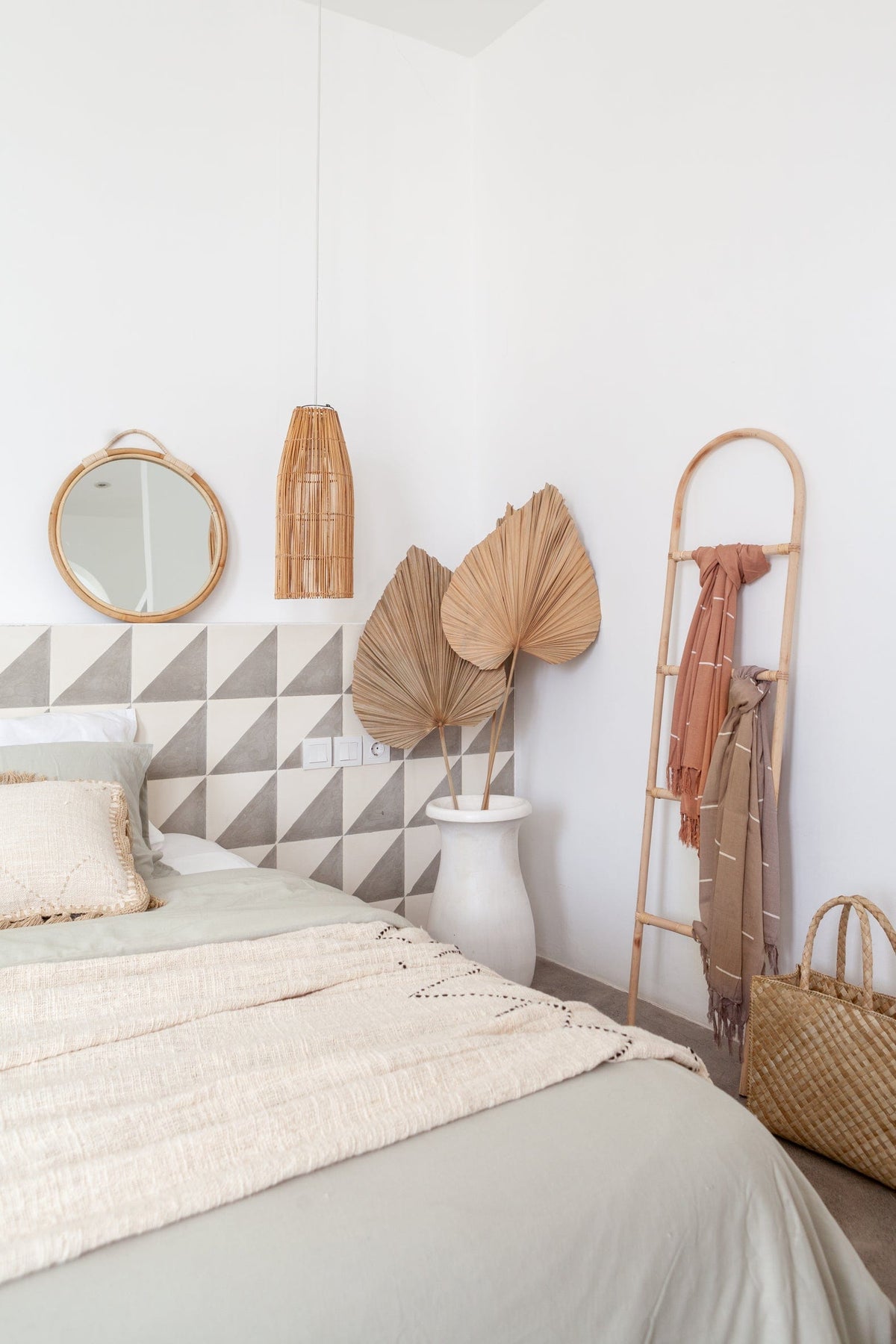Village Thrive Lines Tapestry, terracotta rayon, draped over a wooden ladder beside a bed with triangle-pattern pillows.