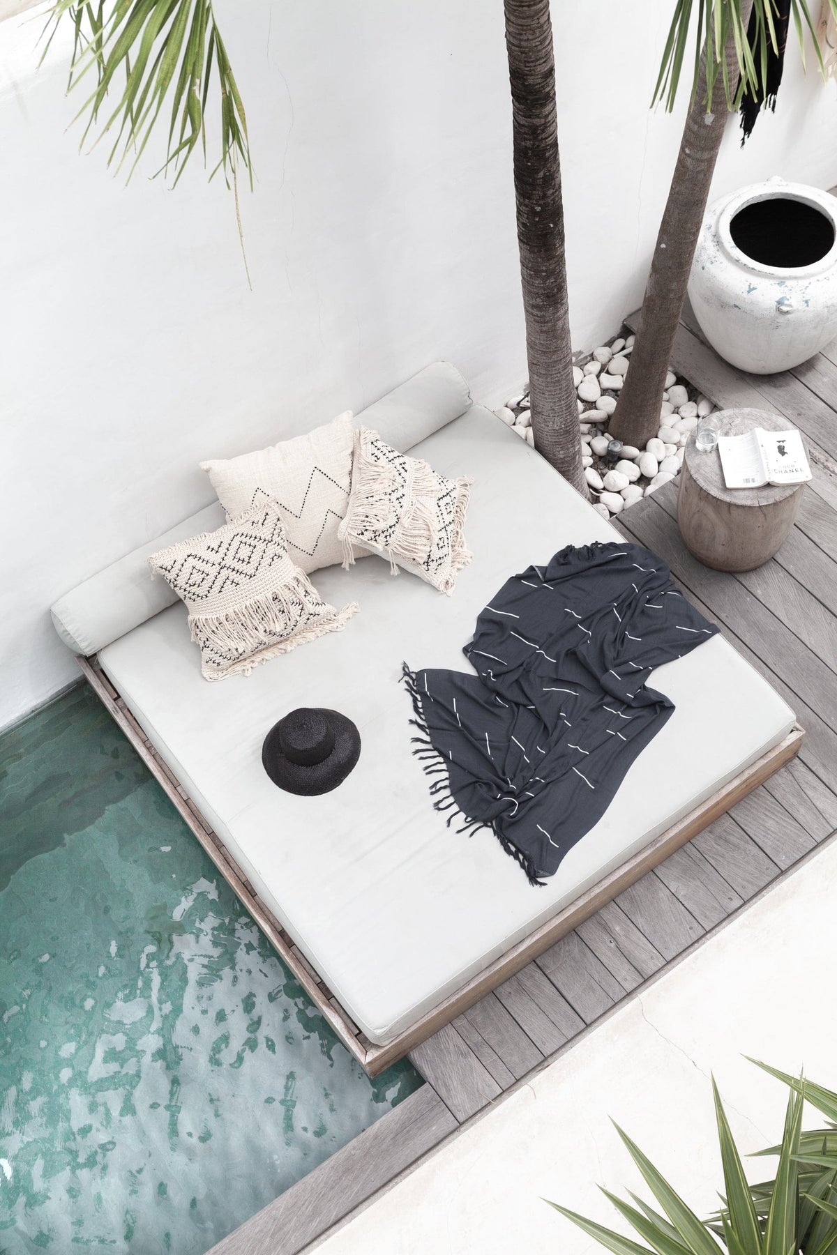 Village Thrive Lines Tapestry, charcoal rayon, draped on a poolside daybed.