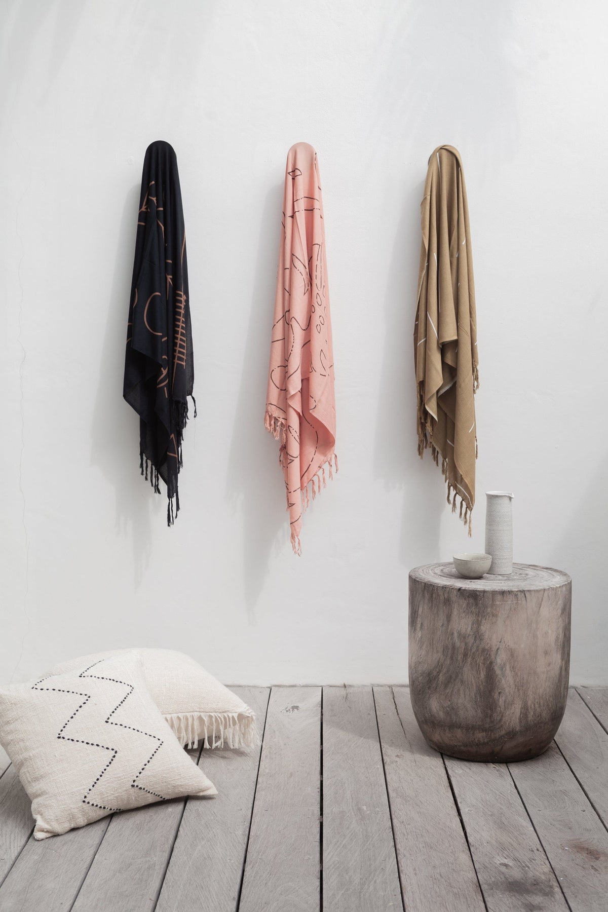 Village Thrive Abstract Tapestry, black, dusty rose, and tan rayon, draped over wall hooks above a floor cushion.