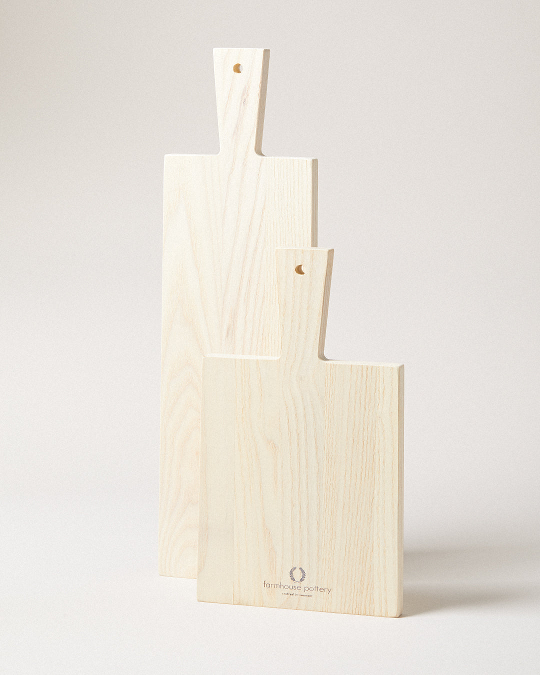 Front product view of three pale wood Pantry Cutting Boards standing upright in graduated sizes with staggered paddle handles.