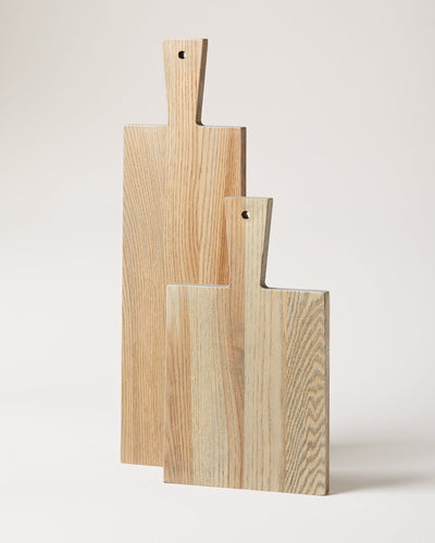 Three pale wood Pantry Cutting Boards in graduated sizes, each with a rectangular body, narrow paddle handle, visible straight grain, and a small hanging hole.