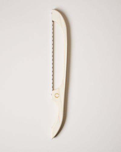 Cream-colored bread bow with a serrated metal blade and gently curved frame displayed against a pale background.