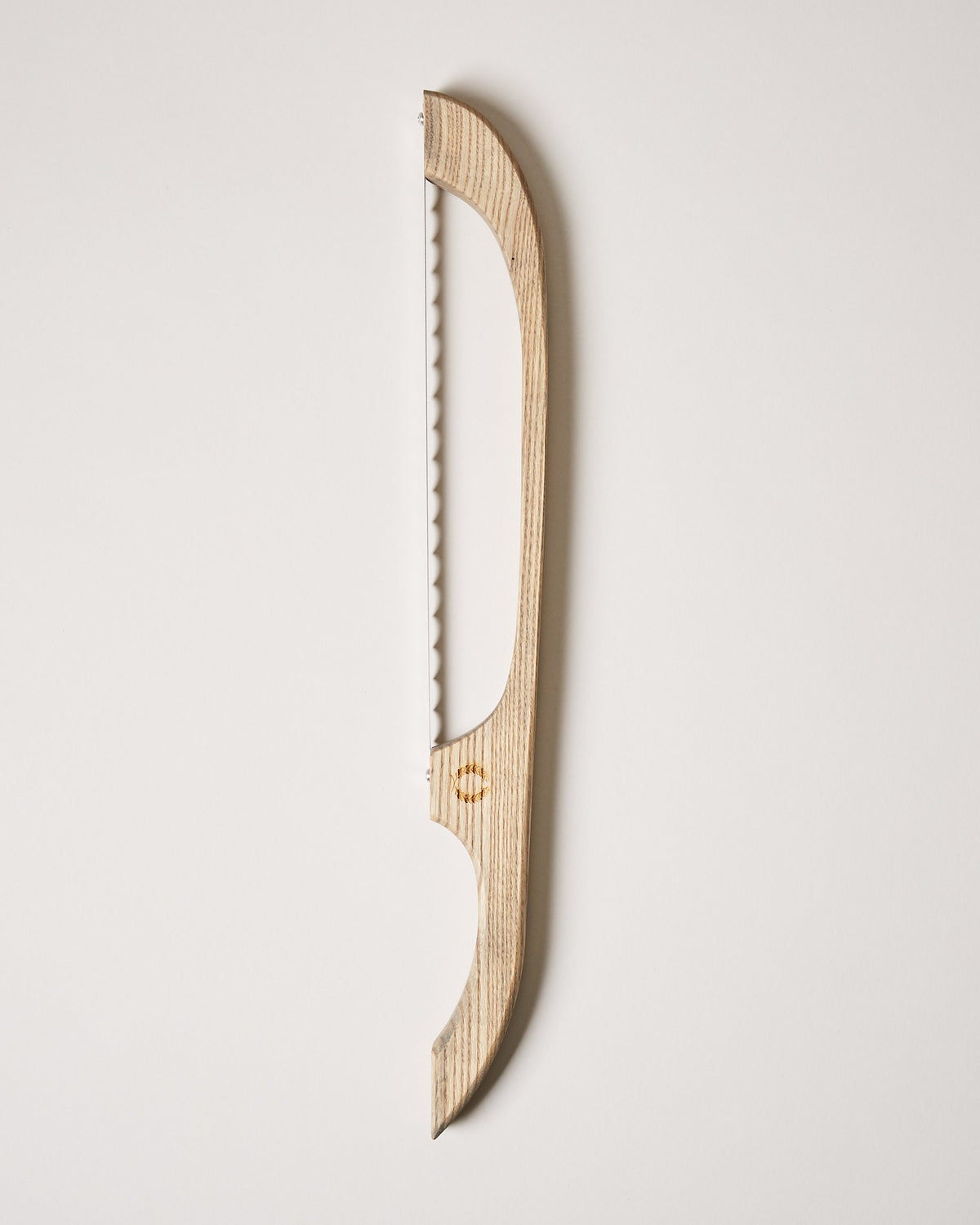 Natural light-wood bread bow with an elongated curved frame and serrated blade shown against a neutral backdrop.