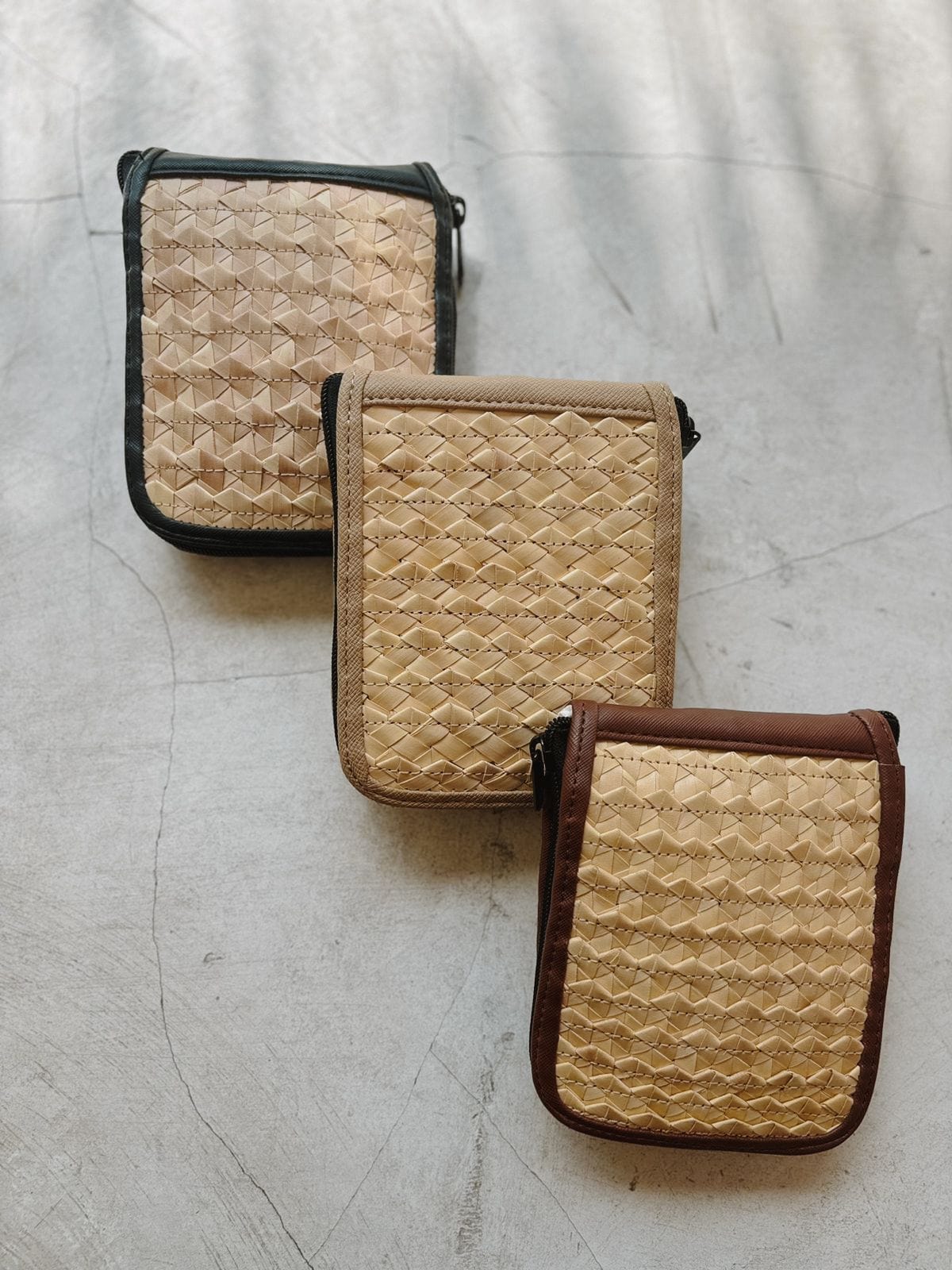Village Thrive Rattan & Canvas Compact Eco Tote Bag, three folded rattan cane cases arranged in a row.