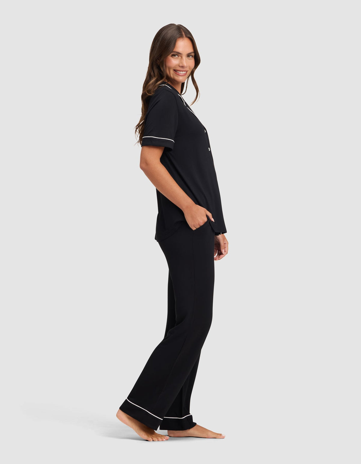 Side view of the black pajama set, showing the loose-fitting top and full-length pants with white piping at the sleeve cuffs and pant hems.