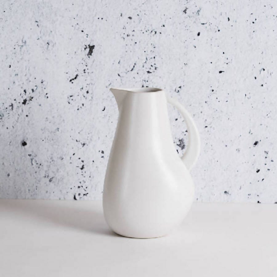 Stoneware pitcher 64 oz in Matte White against textured concrete background