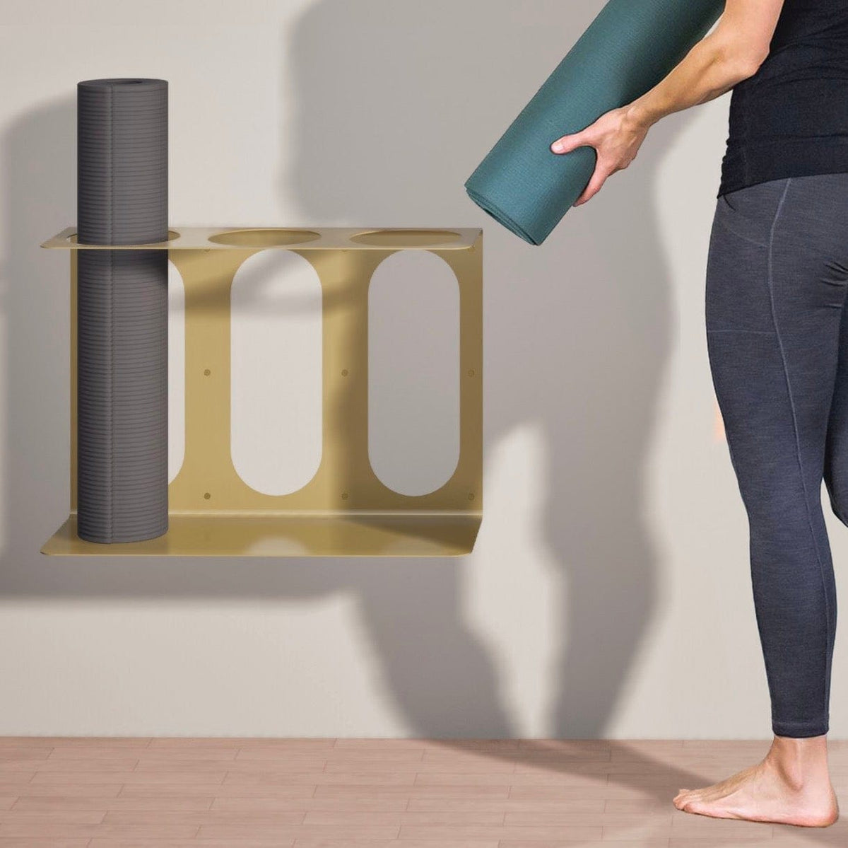 Gold three-slot bracket holding a gray roller while a person positions a teal roller above another opening.