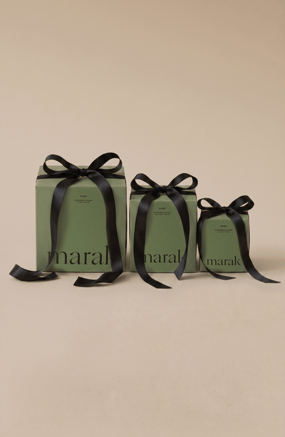Three green boxes with black ribbons on a beige background