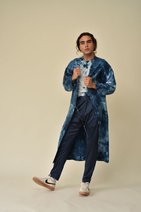 Model walking in a long blue tie-dyed hemp-cotton duster over a gray shirt and navy pants.