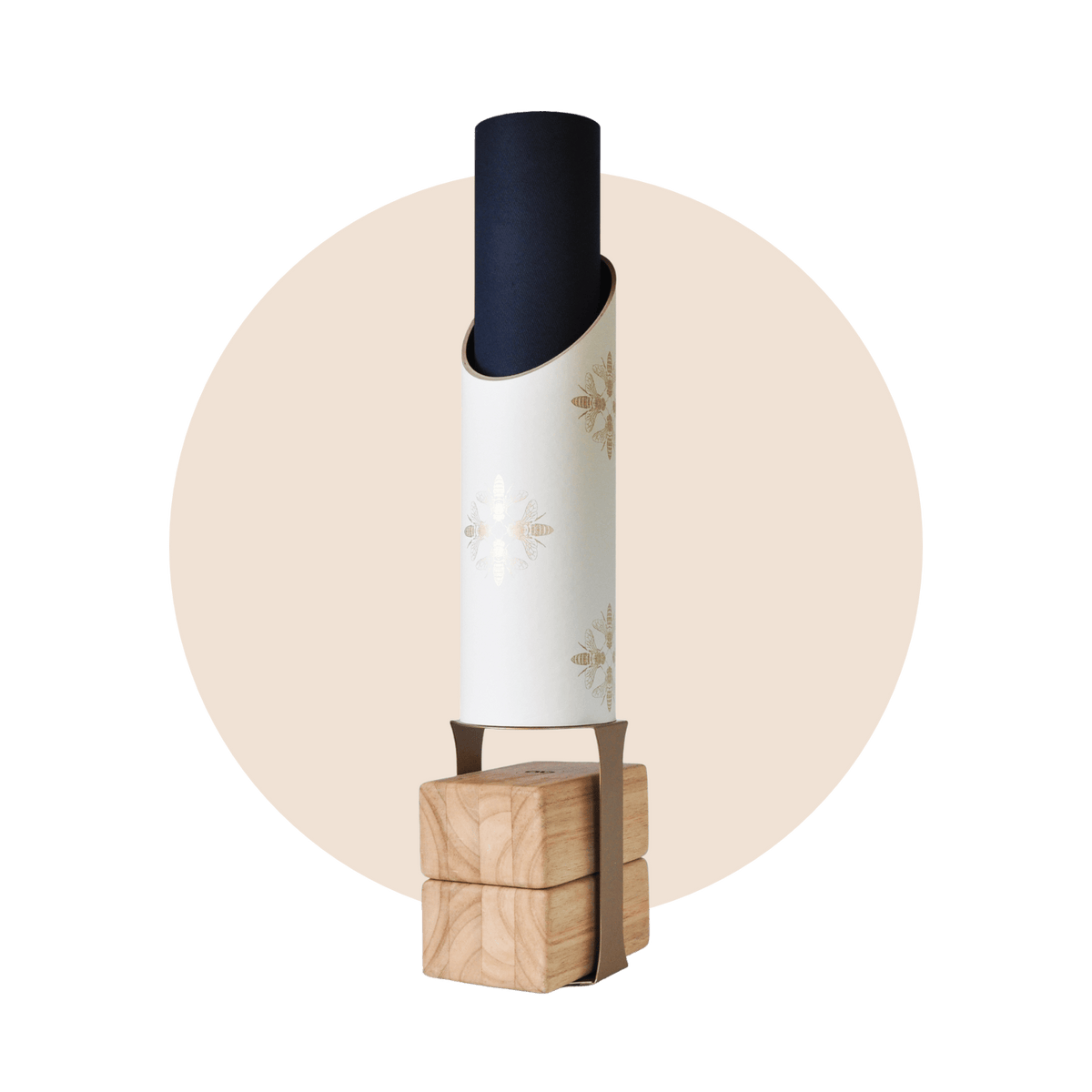 Full Apis storage tube holding a black rolled mat on its wooden block stand, framed by a pale beige circle.