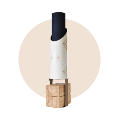 Full Apis storage tube holding a black rolled mat on its wooden block stand, framed by a pale beige circle.