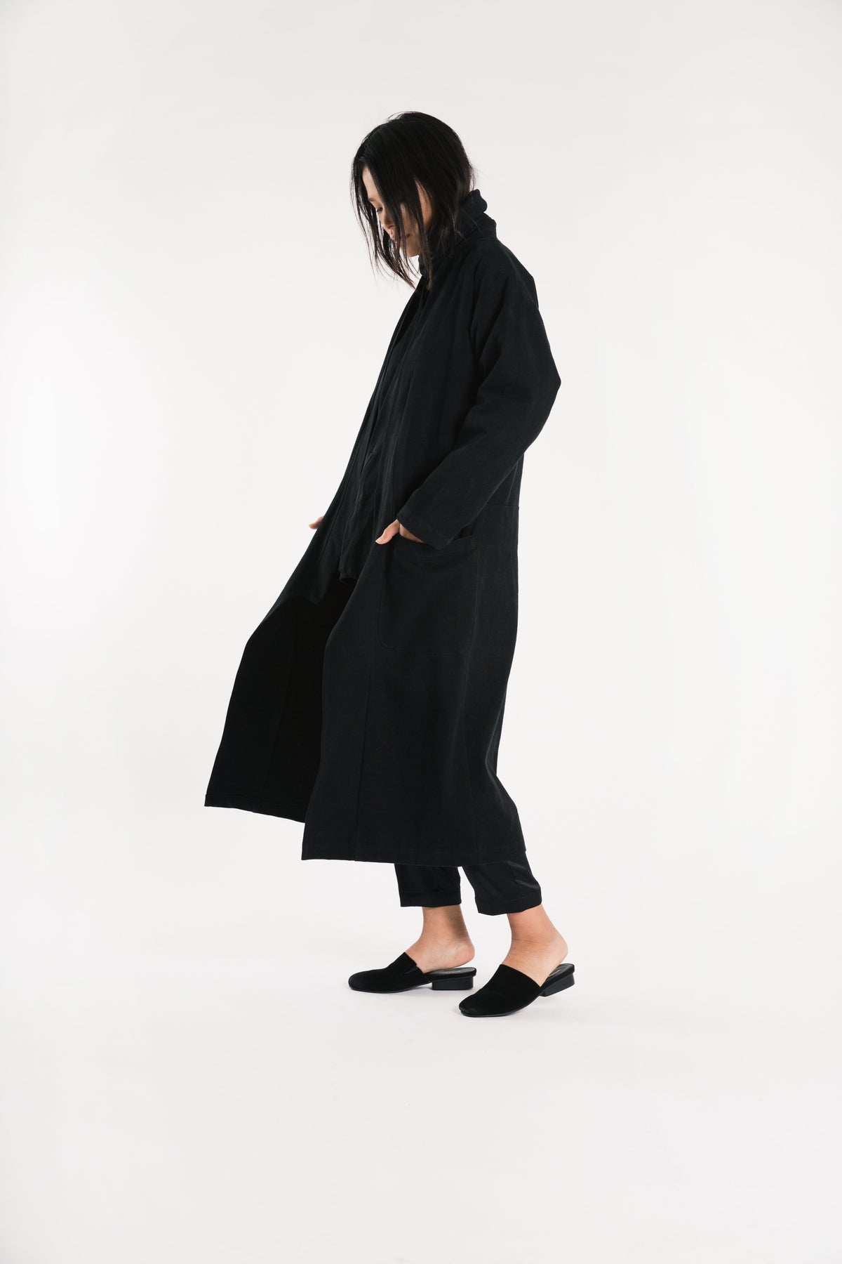 Side view of a model walking in the long black wool kimono over black clothing.