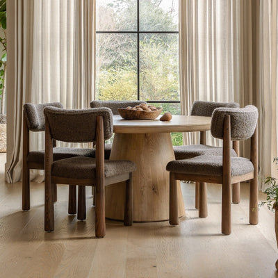 Dining room with wooden table and chairs near large windows by House of Leon.