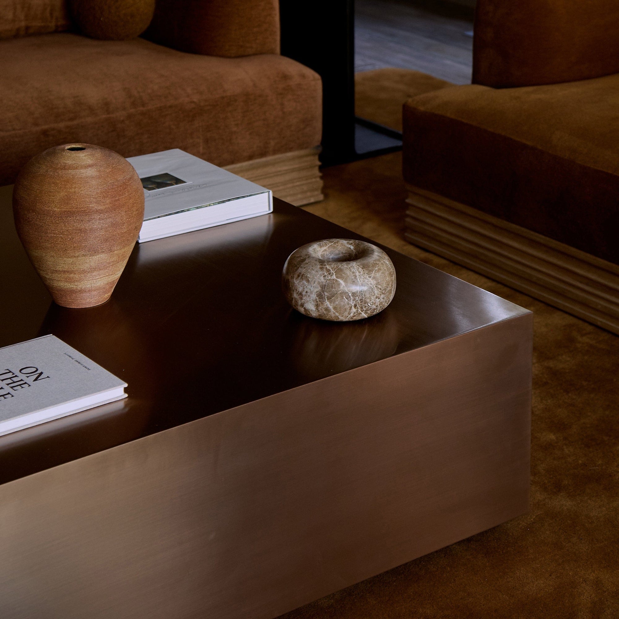 Copper coffee table styled with books and ceramic objects in living space
