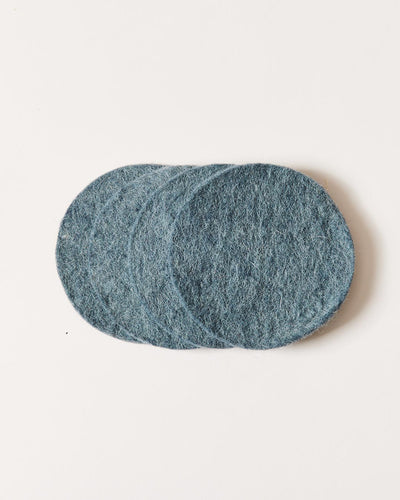 Stack of muted blue-gray felt coasters, slightly fanned to reveal their dense texture and rounded edges.