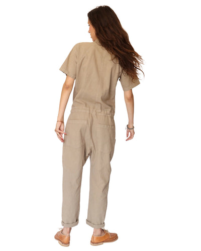Rear view of a model wearing the tan short-sleeve jumpsuit.