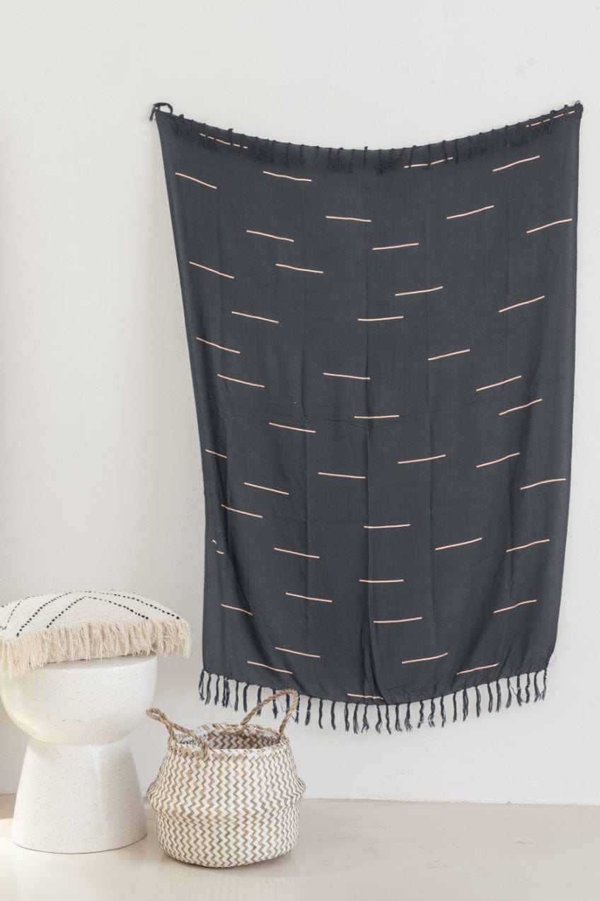 Village Thrive Lines Tapestry, charcoal rayon with white line print, hanging on a wall above woven baskets.