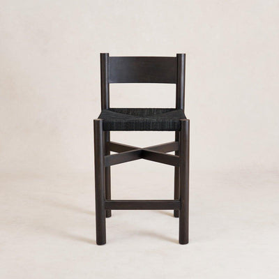 A black Nonna counter stool with a spacious seat constructed from woven jute and a gently curved lower backrest, standing on a white background.