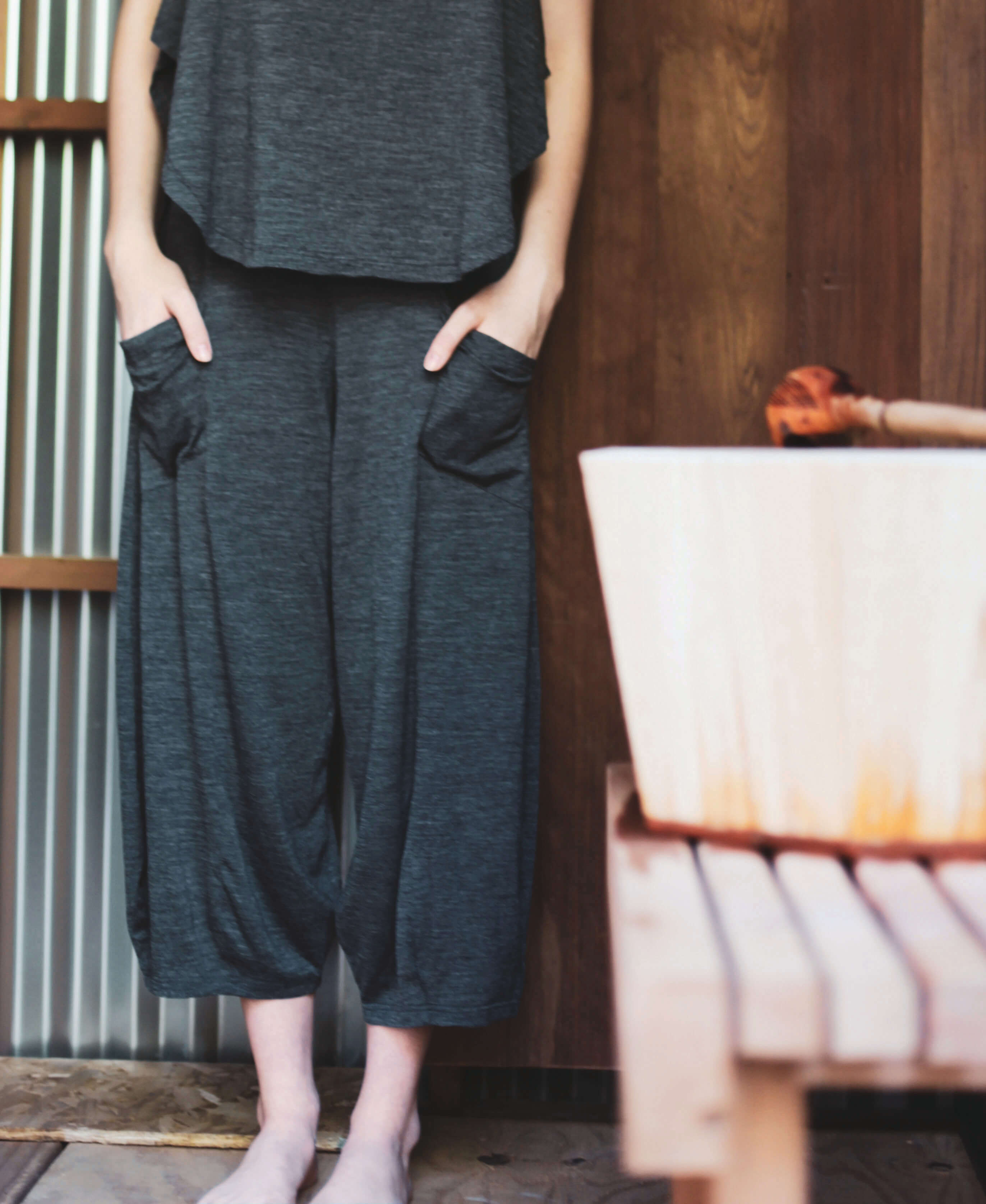 Woman wearing charcoal merino wool lounge pants beside a sauna, designed for recovery, relaxation, and everyday comfort.