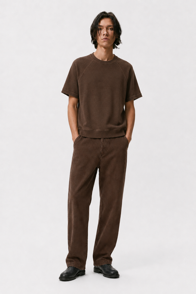 Model wearing a faded brown raglan shirt with matching brown pants and black shoes.