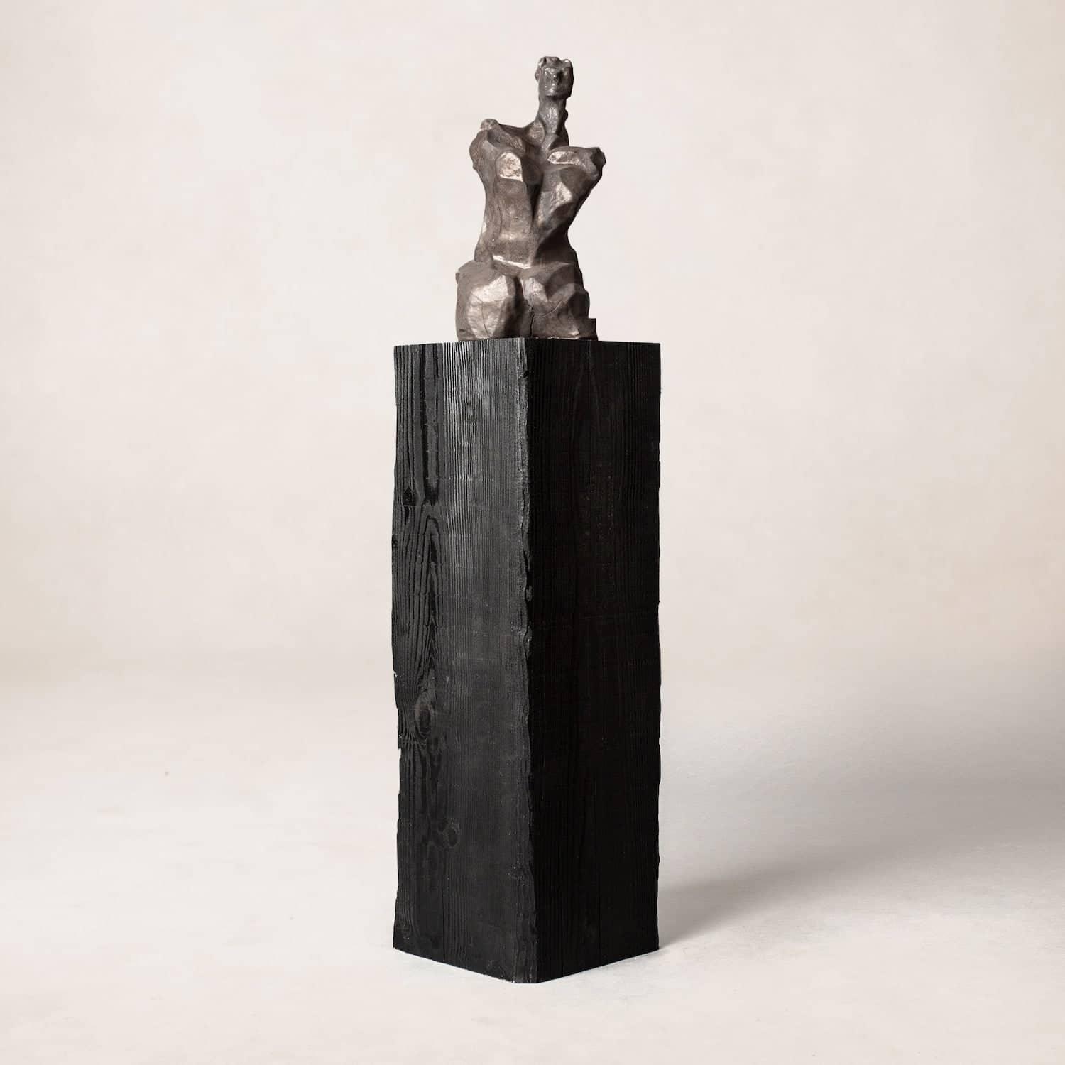Charcoal sculpture pedestal in shou sugi ban wood, minimalist studio view
