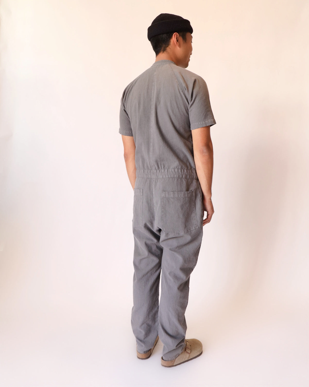 Rear view of a model wearing the gray short-sleeve jumpsuit.