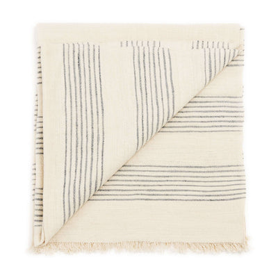 Variously Silica Chalk handwoven throw folded to show its off-white weave, fine gray stripe pattern and short fringed edge
