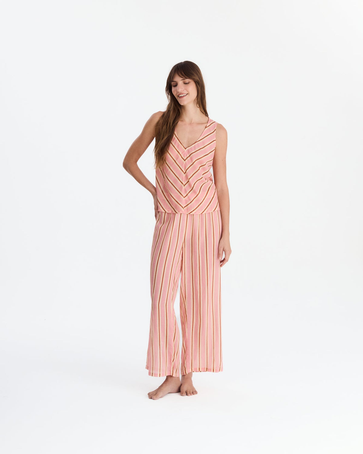 Front view of the model with one hand on her hip, wearing the chevron-striped top and matching ankle-length pants.