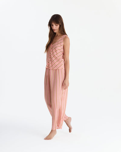 Angled full-length view of the model looking down with one foot lifted, showing the flowing striped pants.