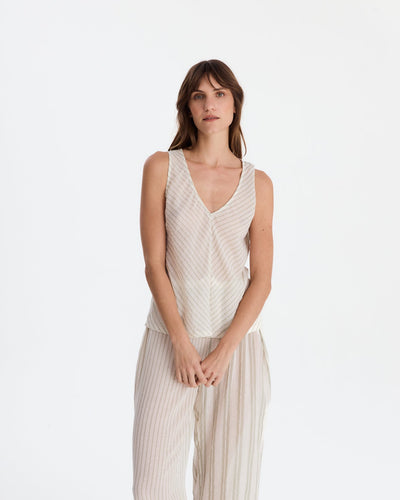 Front view of the model with hands loosely clasped, wearing the striped V-neck top and relaxed pants on a pale studio background.