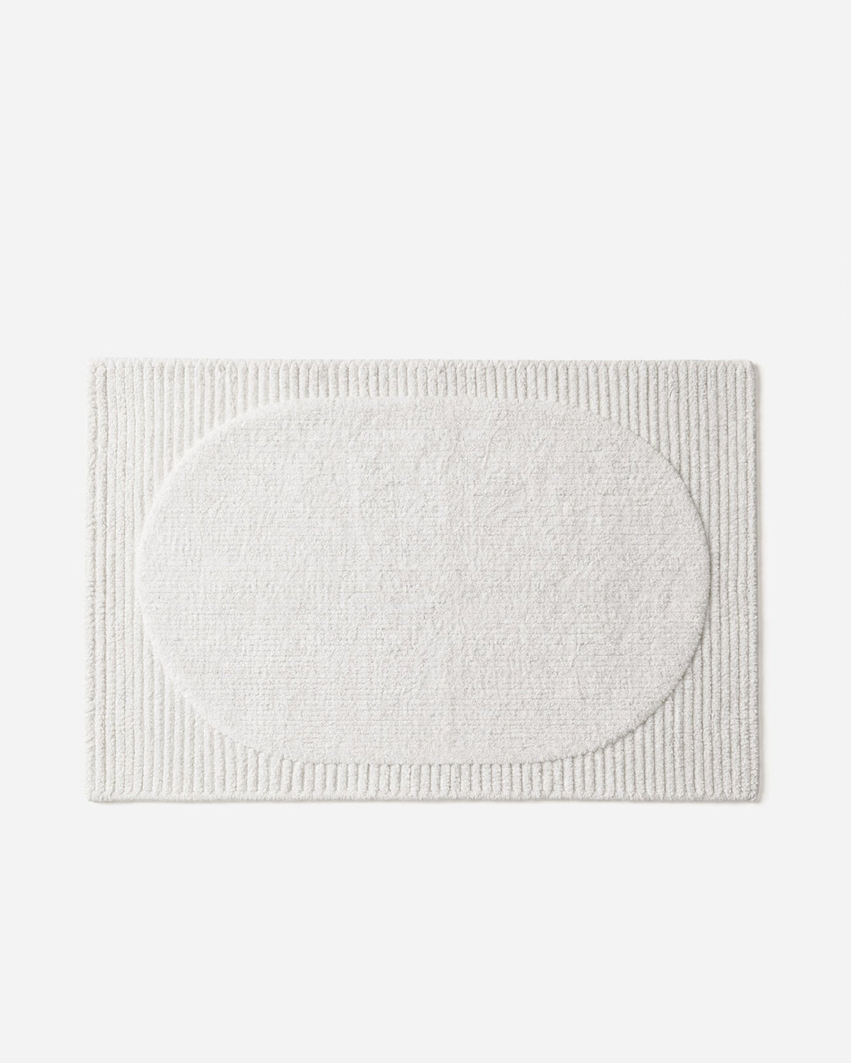 Ivory rectangular Hotel Luxury Bath Rug laid flat on a pale background, featuring a plush oval center surrounded by a ribbed border.