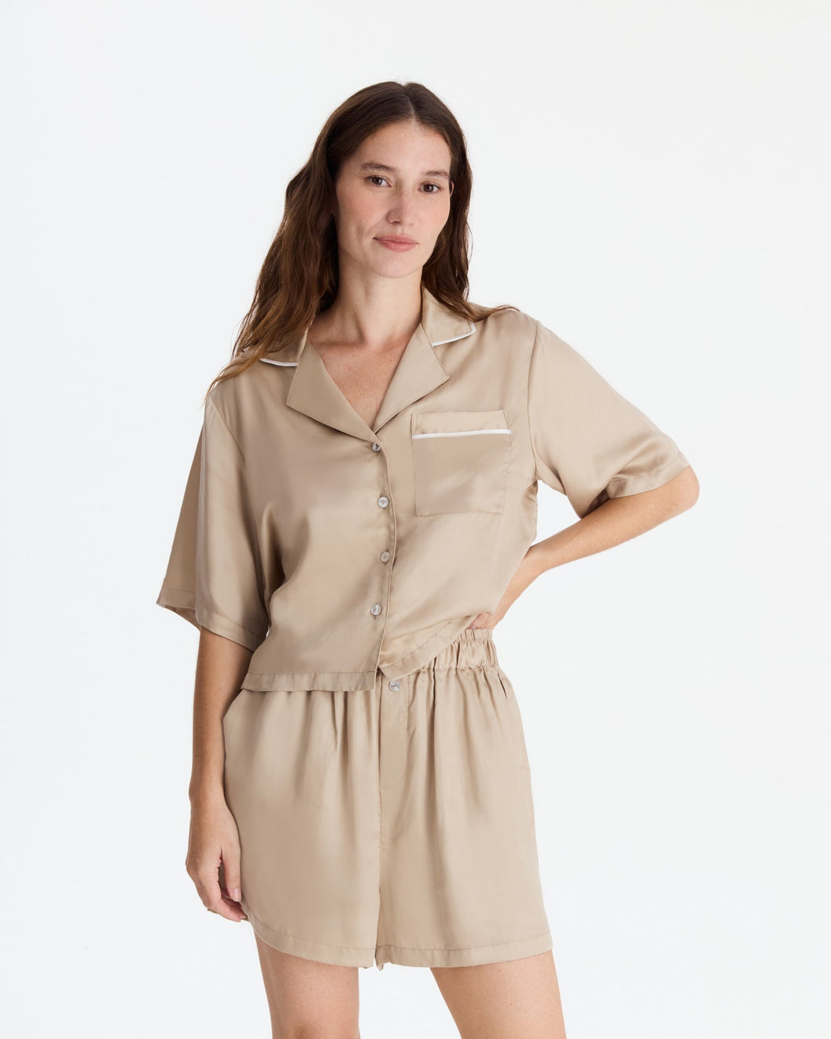 Closer front view of the beige pajama set, showing the shirt’s subtle sheen, pale piping, and buttons, with relaxed shorts and a gathered elastic waistband.