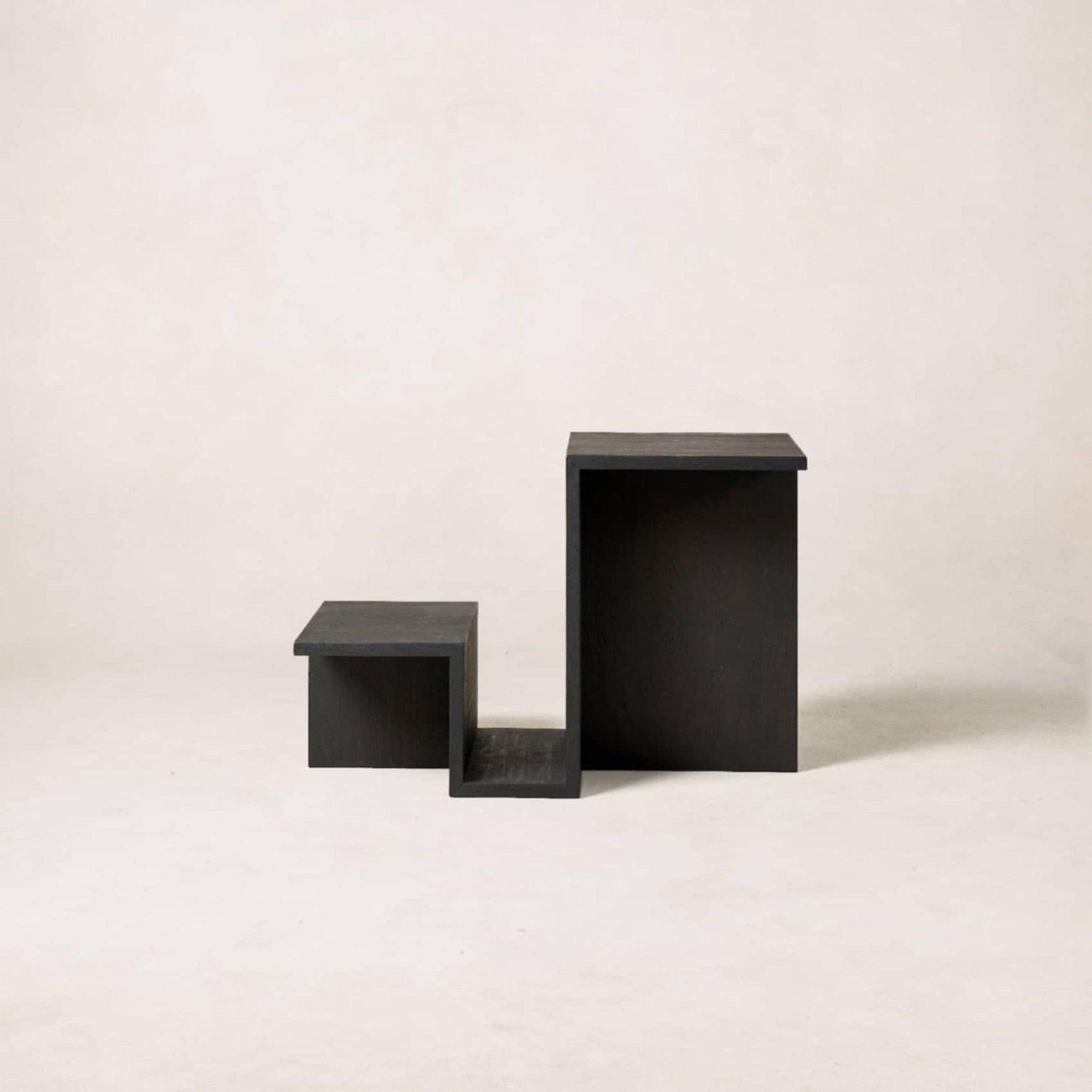 A black tiered side table with a geometric design and a built-in magazine rack, crafted from white oak veneer.