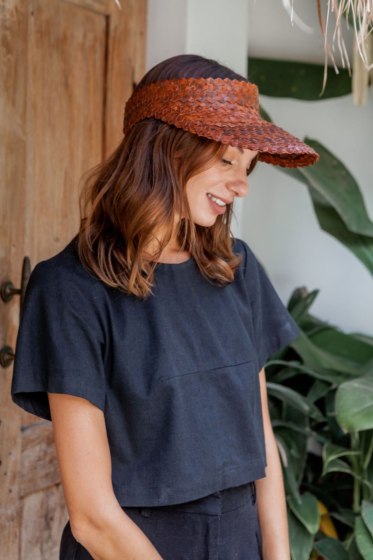 Village Thrive Rattan Sun Visor, clay palm leaf, worn by a model, side profile.
