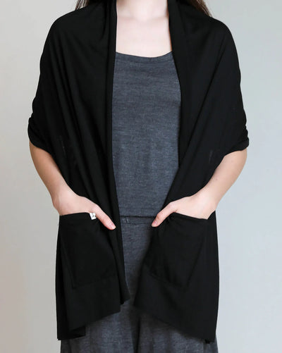 Black merino wool pocket wrap styled as an elegant layering piece for travel, recovery, and everyday wear.